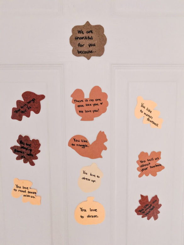 Completed thankfulness craft that includes orange, brown, maroon, and yellow cutouts in fall shapes such as a pumpkin, turkey, acorn, squirrel, and leaves stuck to a white bedroom door