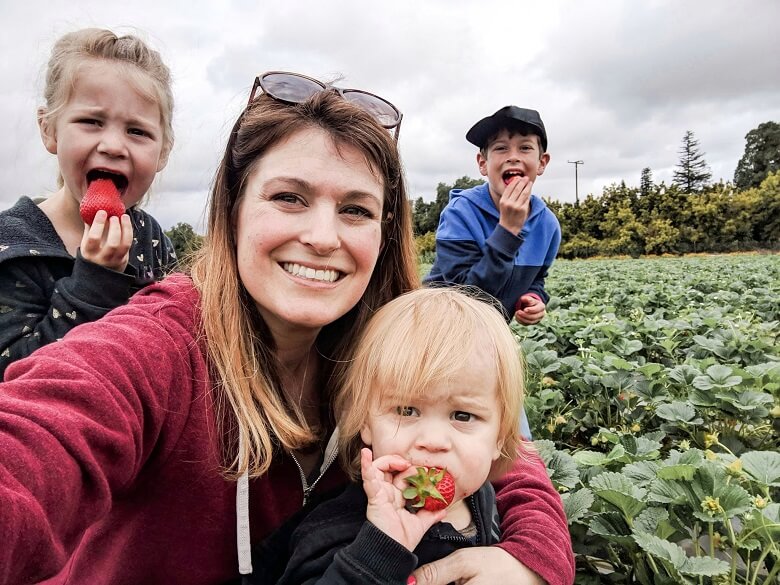 Mother with three kids chaperoning a field trip to a strawberry field
