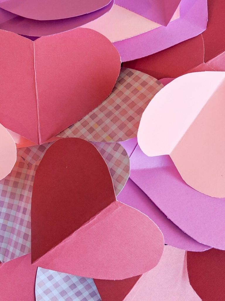 A pile of multicolored hearts cut out of construction paper