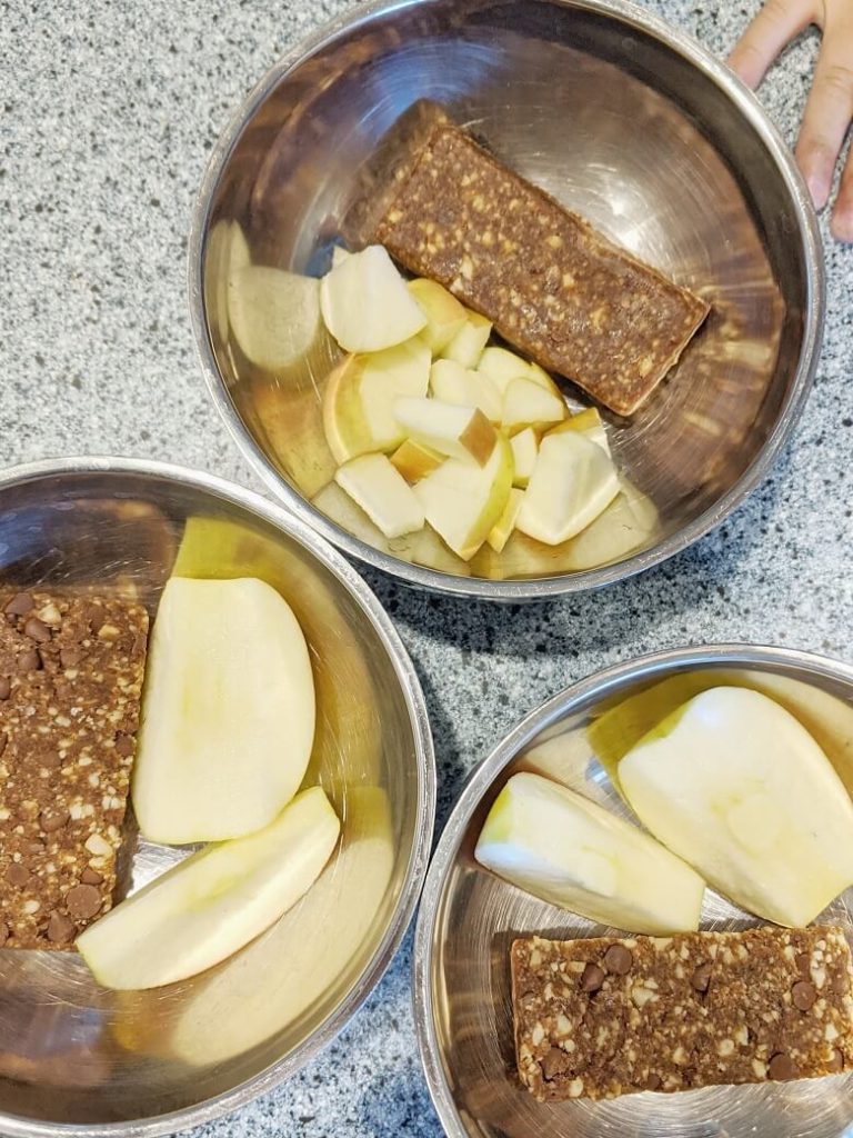 Snack of fruit and nut bars and sliced apples in bowls