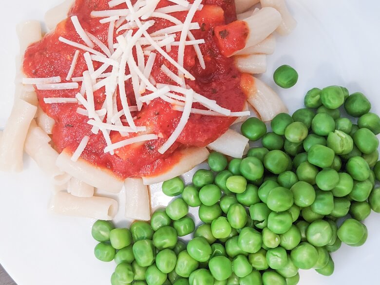 vegan pasta with red sauce, vegan cheese and peas