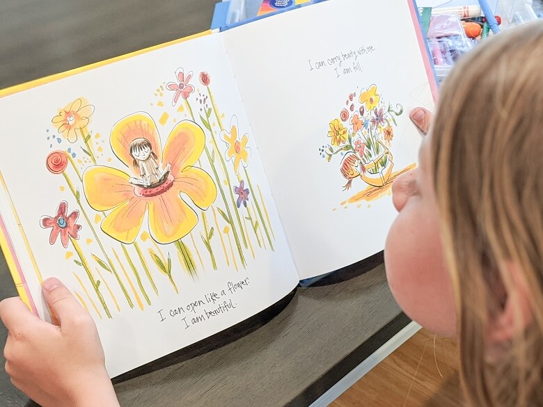 A girl reading the mindfulness children's book called I Am Yoga