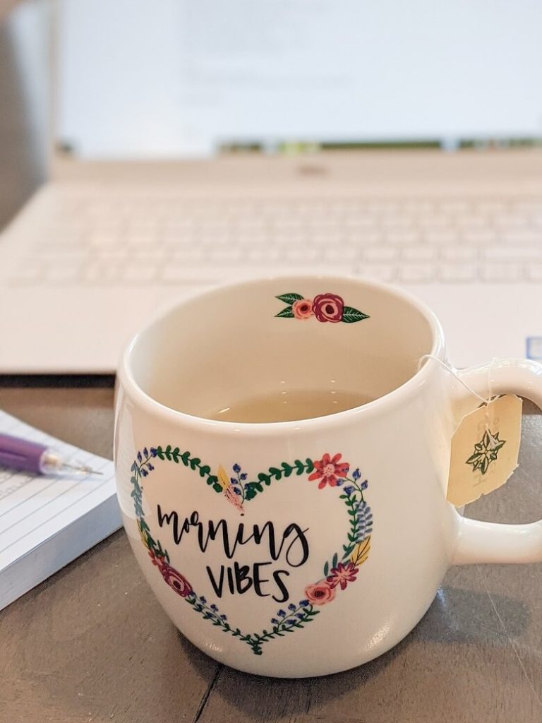 A parent volunteer set up from home with a mug of tea, laptop, pencil and post-it notes to show parents can volunteer at home.
