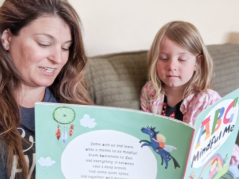 A mom reading a mindfulness children's book called ABC Mindful Me to her daughter