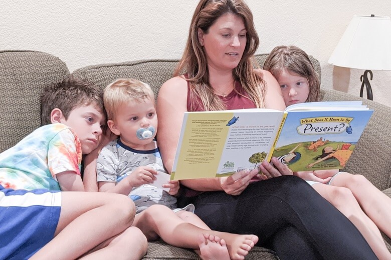 A mom reading the book What Does It Mean to Be Present to her children