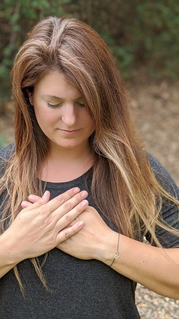 A woman putting her hands over her heart as a coping skill for anxiety to calm the chaos she's feeling
