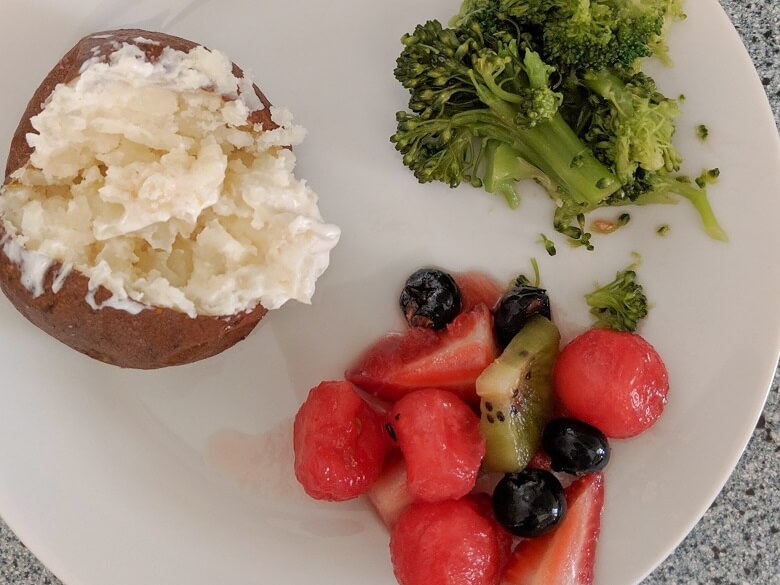 plant-based meal for kids of baked potato, broccoli and fruit salad