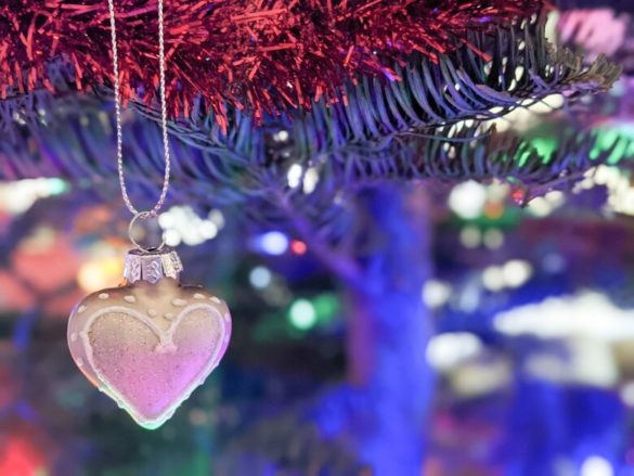 Silver heart ornament on a Christmas tree with lights and garlands