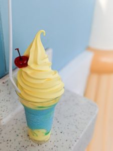 The Pixar Pier Parfait in a cup with a cherry on top and a spoon sticking out of it on a table in DCA.