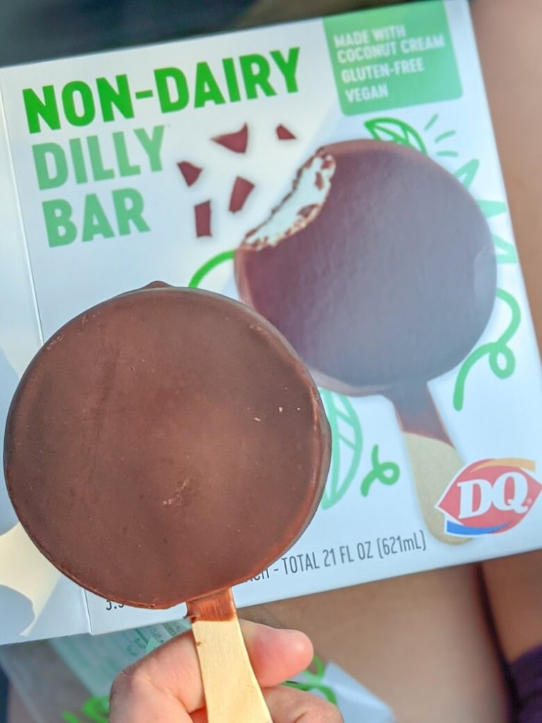 A box of non-dairy Dilly Bars from Dairy Queen with a hand holding an opened dilly bar