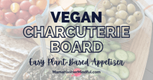 A photo of a vegan cheese board with grape tomatoes, green olives, Persian cucumbers, tabouli, lavash and vegan cheese. Words written over the photo say Vegan Charcuterie Board - Easy Plant-Based Appetizer and the URL reads Mama Has Her Mindful dot com,