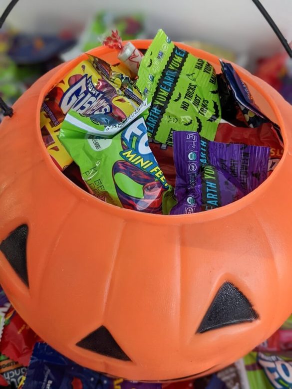Bags of Halloween candy inside of a plastic Jack-o-Lantern.