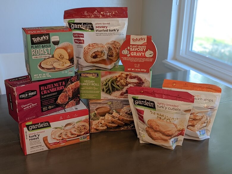 Several plant-based roasts and turkeys stacked on a table from brands such as Gardein, Field Roast, Trader Joe's, Vegetarian Plus and Tofurky.