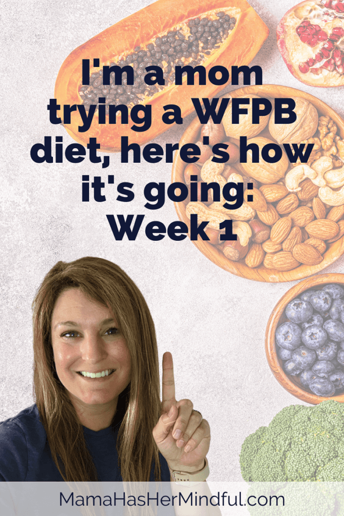 A photo of nuts, seeds, fruits, and vegetables in the background and a woman smiling and holding up a number one sign with her finger. The text on the image reads: I'm trying a WFPB diet, here's how it's going: Week 1. The URL reads: mama has her mindful dot com.