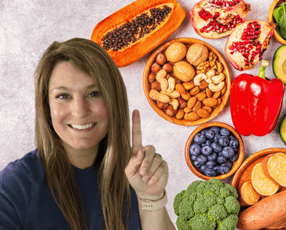 A photo of nuts, seeds, fruits, and vegetables in the background and a woman smiling and holding up a number one sign with her finger.