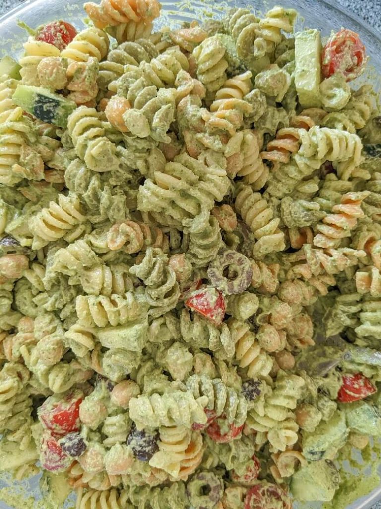 Vegan pesto sauce tossed with a pasta salad in a bowl